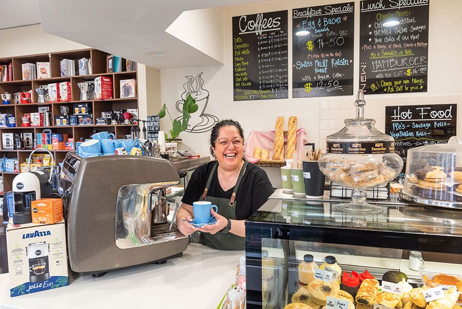 Enza from Spizzico holiding a coffee cup in front of an espresso coffee machine
